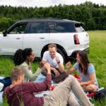 four people having a picnic with a white MINI Cooper in the background.